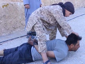 A child soldier is seen decapitating a prisoner in a new ISIS propaganda video. (Video screenshot)