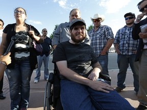 Caleb Medley, center, who was shot in the face in the 2012 Aurora movie theater massacre, sits in a wheelchair near his wife Katie, front left, and other family members as they talk with members of the media after attending the reading of the verdict in the trial of shooter James Holmes at the Arapahoe County District Court, in Centennial, Colo., Thursday, July 16, 2015. (AP Photo/Brennan Linsley)