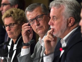 Newfoundland and Labrador Premier Paul Davis, flanked by Ontario Premier Kathleen Wynne, left, and left, and Quebec Premier Philippe Couillard listens at the closing news conference of the summer meeting of Canada's premiers in St. John's on Friday, July 17, 2015. THE CANADIAN PRESS/Andrew Vaughan