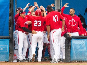 Rene Tosoni (23) is congratulated at the dugout after scoring Canada’s lone run on a second-inning double by Skyler Stromsmoe during last night’s 4-1 loss toe the U.S., in Pan Am Games men’s baseball at Ajax. The gold-medal match will be shown on CBC, but none of the earlier games will have found their way on to local TV screens. (Fred Thornhill, The Canadian Press)