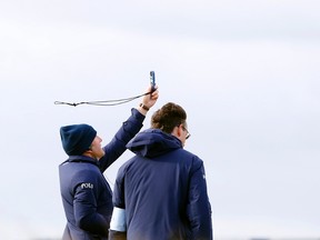 Officials measure the wind speed on the 12th hole as play is suspended during the second round of the British Open Golf Championship on Saturday, July 18, 2015. (AP/Alastair Grant)
