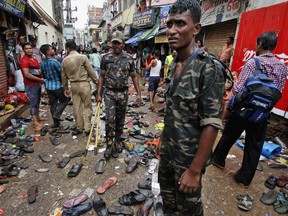 Indian policemen stand at the site near a woman who fainted during a stampede at the annual Rath Yatra or Lord Jagannath chariot procession in Puri, 65 kilometers (40 miles) from the eastern Indian city of Bhubaneswar, India, Saturday, July 18, 2015. Police say the crowd swelled and surged toward a chariot being carried in a procession that caused the stampede, according to PTI. (AP Photo/Biswaranjan Rout)