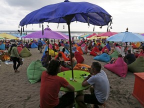 A tourist drinks a bottle of beer during sunset at Seminyak beach, near Kuta, on the resort island of Bali, in this March 3, 2015 file photo. REUTERS/Beawiharta/Files