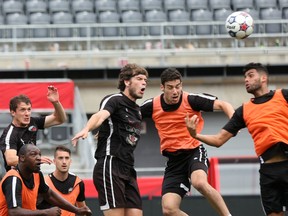 Ottawa Fury FC players, from left, Tommy Heinemann, Drew Becki and Aly Hassan jump for a ball during training at TD Place on Saturday, July 18, 2015. (Chris Hofley/Ottawa Sun)