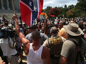 A man holds a Confederate flag during a Black Educators for Justice rally at the South Carolina state house on July 18, 2015 in Columbia, South Carolina. The White Knights of the Ku Klux Klan were scheduled to hold a rally there afterwards, and the government issued a weapons ban around the state house as a precautionary measure.   John Moore/Getty Images/AFP