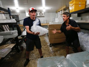 Eddy Melo, right, and Matt Sarty, left, who work for The Iceman company in west Toronto pick an order of 25-pound bags of ice for a customer in  the -7C cooler while the temps outside were 31C with a humidex of 38 on July 18, 2015. (Jack Boland/Toronto Sun)