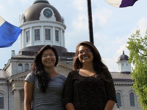 Justina Moosenose and Mikaela Vandell, both from the Northwest Territories, in front of Kingston's city hall with their territory's flag. The teens are living and volunteering in Kingston till August 6. Steph Crosier, The Whig-Standard, Postmedia Network.