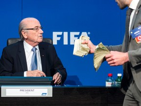As Sepp Blatter took his seat, comedian Simon Brodkin rose from a front-row seat to speak and shower the FIFA president with what appeared to be fake money bills. (Ennio Leanza/Keystone via AP)