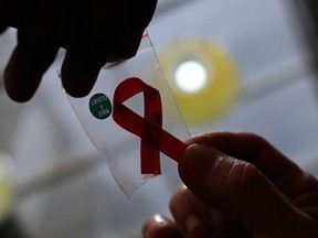 A nurse  hands out a red ribbon to a woman, to mark World Aids Day, at the entrance of Emilio Ribas Hospital, in Sao Paulo December 1, 2014. REUTERS/Nacho Doce