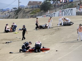 In this Sunday, July 19, 2015, photo, medical and track personnel attend to downed riders after a chain reaction crash on the first lap of a World Superbike race at Mazda Raceway at Laguna Seca in Monterey, Calif. (Nic Coury/Monterey County Weekly via AP)