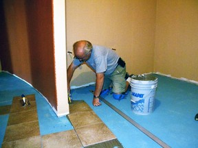 Doug Wolfe of Wolfe Flooring lays down tile in one of the Crystal Palace's new washrooms last Wednesday July 15. The washroom renovations have been ongoing since May. GALEN SIMMONS/MITCHELL ADVOCATE