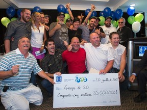 A group of 20 Rona hardware employees pose with their 55 million dollar Lotto Max jackpot cheque, the second largest in Canadian history, at a news conference, Monday, July 20, 2015 in Montreal. (THE CANADIAN PRESS/Ryan Remiorz)