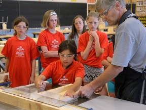 Sarah Harvey, 11, is helped by shop tech Albert Fekken during the Girls Exploring Technology Summer Camp at Fanshawe College Monday. (MORRIS LAMONT, The London Free Press)