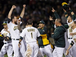 Oakland Athletics' Ike Davis, left, celebrates after a review of a play at first base showed he was safe with an RBI single that drove in the game-winning in the 10th inning of a baseball game against the Toronto Blue Jays Wednesday, July 22, 2015, in Oakland, Calif. The A's won 4-3 in 10 innings. (AP Photo/Ben Margot)