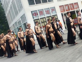 In this Wednesday, July 22, 2015, photo, men dressed in Spartan-style costumes walk through a commercial plaza in Beijing. A salad store paraded dozens of half-naked Western men dressed as Spartans through China's capital as a publicity stunt, causing a stir and drawing a crackdown by police who were photographed restraining some of them on the ground. (Photo via AP)