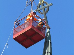 A crew from Imperial Roofing in Sarnia removes the copper cross from the steeple at St. Andrew's Presbyterian Church on Thursday July 23, 2015 in Sarnia, Ont., for repairs. The cross was bent over by high winds during last weekend's storm. (Paul Morden, The Observer)