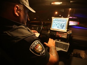 Const. Corey MacNeil checks the record of a man he pulled over in the Cardwell-Kirkwood area, after the man's car cut him off in the middle of an intersection. Ottawa Sun files.