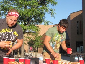 Jesse Kankula, left, gets ready to eat another hot dog after dunking it in water. The strategy proved to be successful as the Ridgetown resident won the contest in downtown Chatham. The event was held to benefit the Chatham-Kent Women's Centre. Also pictured is Zach Trinetti of Chatham.