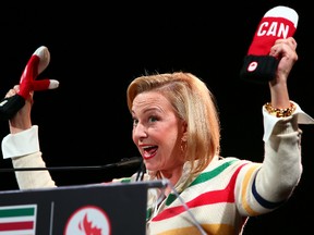 The Bay president and CEO Bonnie Brooks shows off the new mittens as the Canadian Olympic Committee unveils Canada's uniforms for the Sochi Olympics at the Distillery District in Toronto in this October 30, 2013 file photo. (Dave Abel/Postmedia Network)