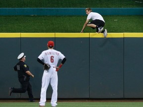 A fan jumps over the centre field wall as he evades police while Cincinnati Reds center fielder Billy Hamilton, centre, looks on in the eighth inning in the second game of a doubleheader against the Chicago Cubs in Cincinnati, Wednesday, July 22, 2015. (AP Photo/John Minchillo)