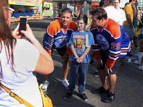 Kenton Gardiner gets his picture taken with Oiler Alumni Sean Brown (l) and Louie DeBrusk during Monday Morning Magic at the K-Days grounds. Photo by Perry Mah/Edmonton Sun