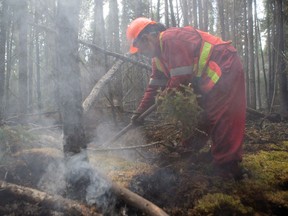 Firefighter Lyris Bird-LaVallee uses an axe to battle a forest fire near Weyakwin, Saskatchewan, on Wednesday, July 15, 2015. About 1,000 fire evacuees in Saskatchewan have received the all-clear to head home. THE CANADIAN PRESS/Pool/Liam Richards-The StarPhoenix