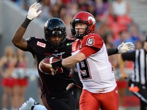 Ottawa Redblacks' Aston Whiteside moves in to knock the ball from the hand of Calgary Stampeders' Bo Levi Mitchell during second quarter CFL football action in Ottawa on Friday, July 24, 2015. Whiteside gained possession of the ball to make an interception. THE CANADIAN PRESS/Sean Kilpatrick