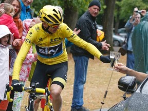 Team Sky rider Chris Froome of Britain toasts his team with a glass of champagne as he rides during the final stage of the 102nd Tour de France July 26, 2015 in Paris. (REUTERS/Sebastien Nogier/Pool)