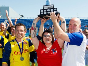 (left to right) Matthew Harris, Cst. Daniel Woodall's widow Claire Woodall, and Bruce McGregor hold up the Woodall Cup at Clarke Stadium, in Edmonton Alta. on Sunday July 26, 2015. The charity soccer game pitted a team of British ex-pats against Edmonton Police Service officers. The game ended in a 2-2 tie. David Bloom/Edmonton Sun/Postmedia Network