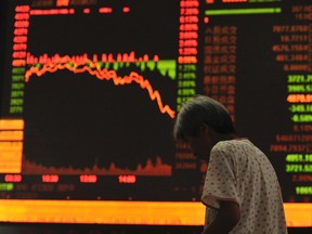 An investor stands in front of an electronic board showing stock information at a brokerage house in Fuyang, Anhui province, July 27, 2015. China stocks plunged more than 8%, their biggest one-day drop in more than eight years. (REUTERS/Stringer)