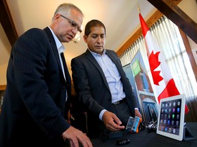 EMILY MOUNTNEY-LESSARD/THE INTELLIGENCER
FedDev Minister Gary Goodyear learns about Tecla, hardware and software tools aimed at making touch screen devices easier to use for people with disabilities. At right is Mauricio Mezza, CEO of Komodo OpenLab, the parent company of Tecla. They are shown here during Monday’s federal government funding announcement in Prince Edward County.