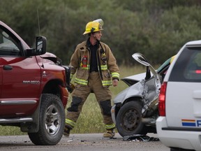 A firefighter walks between two vehicles involved in a very serious crash west of Calgary on Monday, July 27, 2015. One person was killed. (Mike Drew/Calgary Sun)