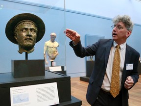 In this Monday, July 27, 2015 photo, Kenneth Lapatin, associate curator at the J. Paul Getty Museum, gestures toward a sculpture which is part of the "Power and Pathos: Bronze Sculpture of Hellenistic World" exhibit in Los Angeles. (AP Photo/Nick Ut)