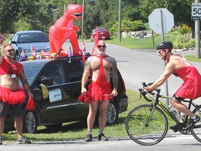 Lucien Ollivier, left, and Mark Fisher, centre, cheer on one of the 200 riders in the annual Friends For Life Bike Rally as they entered Kingston, Ont. on Tuesday, July 28, 2015. The ride raises money for HIV/AIDS support. Michael Lea/The Whig-Standard/Postmedia Network.