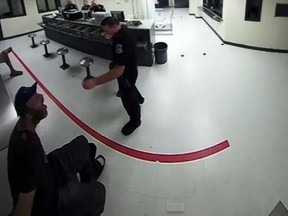 A surveillance video from inside the Sarasota County Jail showed Officer Andrew Halpin of the Sarasota Police Department standing near the man and trying to toss peanuts into the man's mouth. (YouTube screengrab)