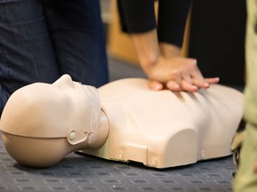 A group of students learn CPR chest compressioon on a dummy. (Fotolia)