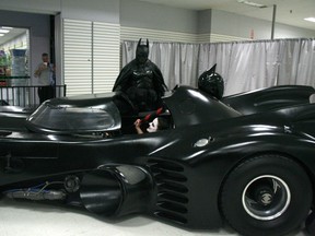 Stephen Lawrence, dressed as batman, stands near his replica Batmobile as Kristen Mason sits in the driver seat during a charity appearance at a mall in Kingston, Ont. (THE CANADIAN PRESS)