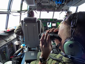 Petty Officer 1st Class Mike Crosby, right, scans the surface of the Atlantic Ocean through his binoculars from a Coast Guard HC-130J, Tuesday, July 28, 2015, while searching for Florida teens Perry Cohen and Austin Stephanos, Tuesday, July 28, 2015. (Senior Chief Petty Officer Sarah B. Foster/U.S. Coast Guard via AP)