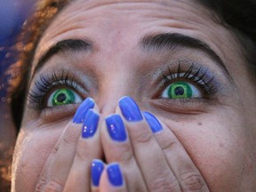 A Brazil soccer fan wearing contact lenses that mimic the Brazilian flag reacts as she watches her team play Germany in a World Cup semifinal game via live telecast inside the FIFA Fan Fest area on Copacabana beach in Rio de Janeiro, Brazil on July 8, 2014. Health Canada says it will regulate cosmetic or decorative contact lenses in the way it oversees the sale of corrective lenses. (The Canadian Press/AP, Leo Correa)