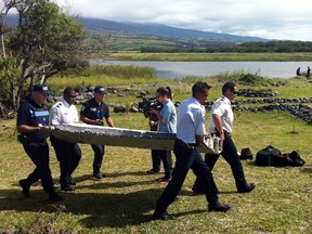 Police carry a piece of debris from an unidentified aircraft found in the coastal area of Saint-Andre de la Reunion, in the east of the French Indian Ocean island of La Reunion, on July 29, 2015.  (AFP/YANNICK PITOU)