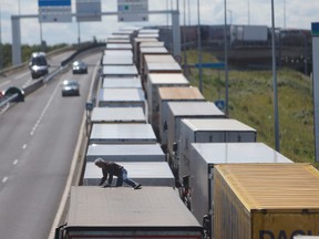 A driver climbs on his truck as he waits to cross the English channel, in Calais, northern France, Wednesday, July 29, 2015. Migrants rushed the tunnel linking France and England repeatedly for a second night on Wednesday and one man was crushed by a truck in the chaos, deepening tensions surrounding the thousands of people camped in this northern French port city. (AP Photo/Thibault Camus)