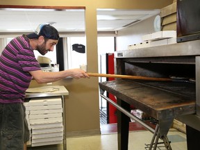 Despite the heat, Paul DiSalle, of Frenchy's Pizza, places a pizza in the oven on Wednesday. John Lappa/Sudbury Star
