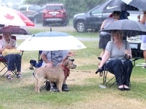 Mike and Liz Chorkawy, and Annie the dog attempt to keep dry while watching a concert at the concert and farmers market at the Anderson Farm Museum in Lively on Wednesday evening. The concert and farmers market is held every Wednesday in July and August. John Lappa/The Sudbury Star