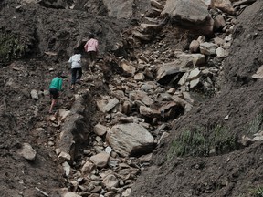 Nepalese youth walk through the debris  after a landslide in Lumle village, about 200 kilometers (125 miles) west of Kathmandu, Nepal, Thursday, July 30, 2015. (AP Photo/Niranjan Shrestha)