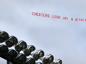 A banner towed by an airplane over the New England Patriots' practice field reads "Cheaters Look Up!" as it passes the lighting rack above Gillette Stadium during an NFL football training camp in Foxborough, Mass., Thursday, July 30, 2015. (AP Photo/Charles Krupa)