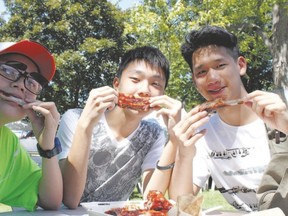 From left, Chen Kehan, 14, Chen Castle, 18, and Li Ming, 18, all visiting London from China for a English language summer camp at Centennial Hall, stopped by London Ribfest at Victoria Park for a rib lunch Thursday. (JOE BELANGER, The London Free Press)