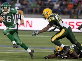 Saskatchewan Roughriders' Brett Smith (16) dodges the tackle from Edmonton Eskimos' Ryan Hinds (34) and Deon Lacey (40) during second half CFL pre-season action in Fort McMurray, Alta., on Saturday June 13, 2015. Smith will make his first CFL start Friday night when the Roughriders visit the Eskimos. THE CANADIAN PRESS
