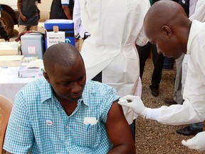 In this March 7, 2015 file photo, a health worker, right, cleans a man's arm before injecting him with a Ebola vaccine in Conakry, Guinea.   (AP Photo/Youssouf Bah, File)