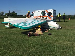 Firefighters are seen helping a pilot who's plane flipped while landing at Skyview Airport in Reece's Corners Friday, a witness says. The pilot appeared OK, the witness said. Handout/Sarnia Observer/Postmedia Network