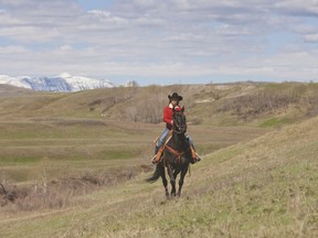 PHOTO COURTESY OF HEARTLAND. Amy Fleming, portrayed by Amber Marshall, rides along a ridge with the Rocky Mountains in the background. The red jacket worn by Marshall’s character Fleming is on display at the museum.